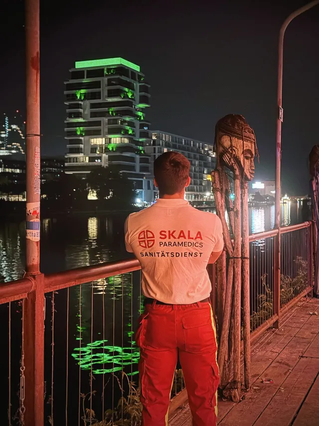 Sanitäter von SKALA Paramedics an einem Geländer mit Blick auf die beleuchtete Stadt