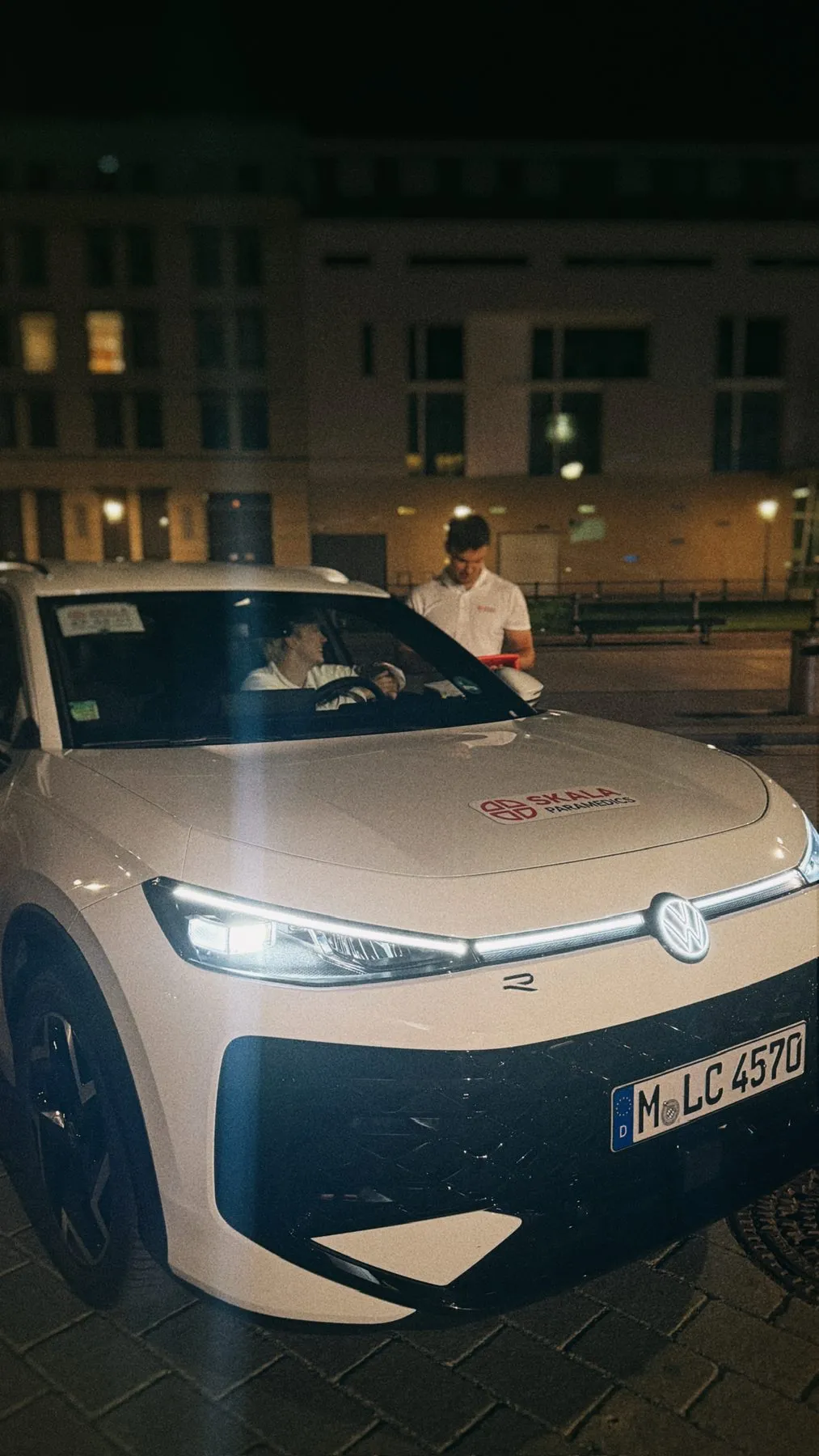 Weißes SKALA-Einsatzfahrzeug bei Nacht vor beleuchteten Gebäuden