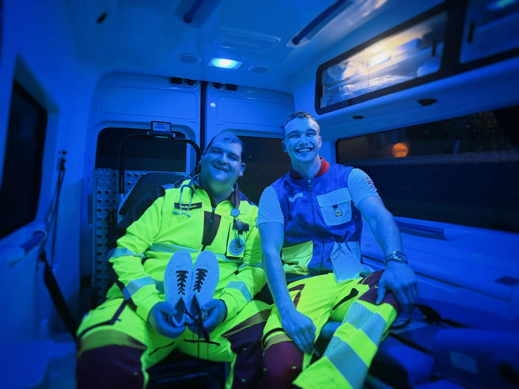 Zwei Sanitäter im blau beleuchteten Innenraum eines Krankentransportwagens