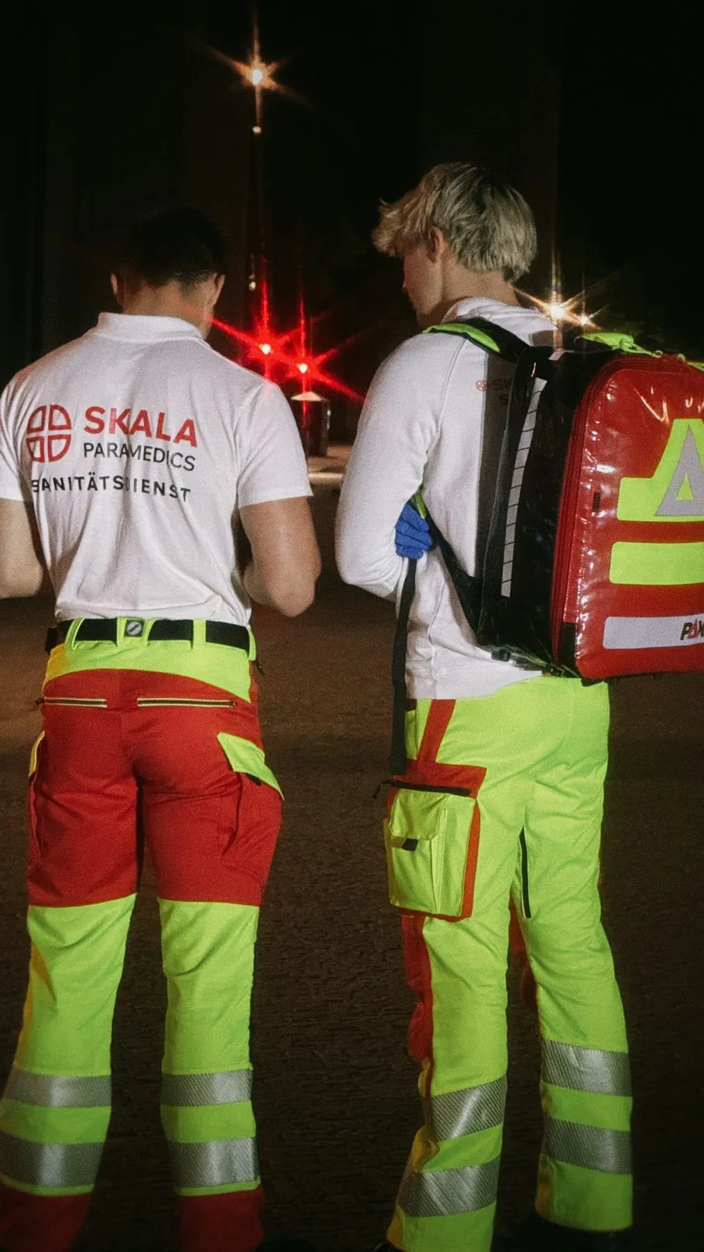 Zwei Sanitäter mit SKALA-Rückenaufdruck und Notfallrucksack bei Nacht