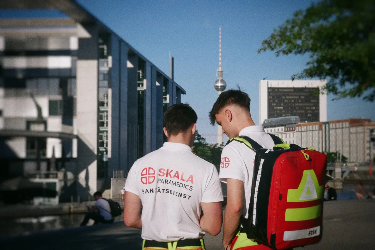 Zwei Sanitäter mit Notfallrucksack, im Hintergrund der Berliner Fernsehturm
